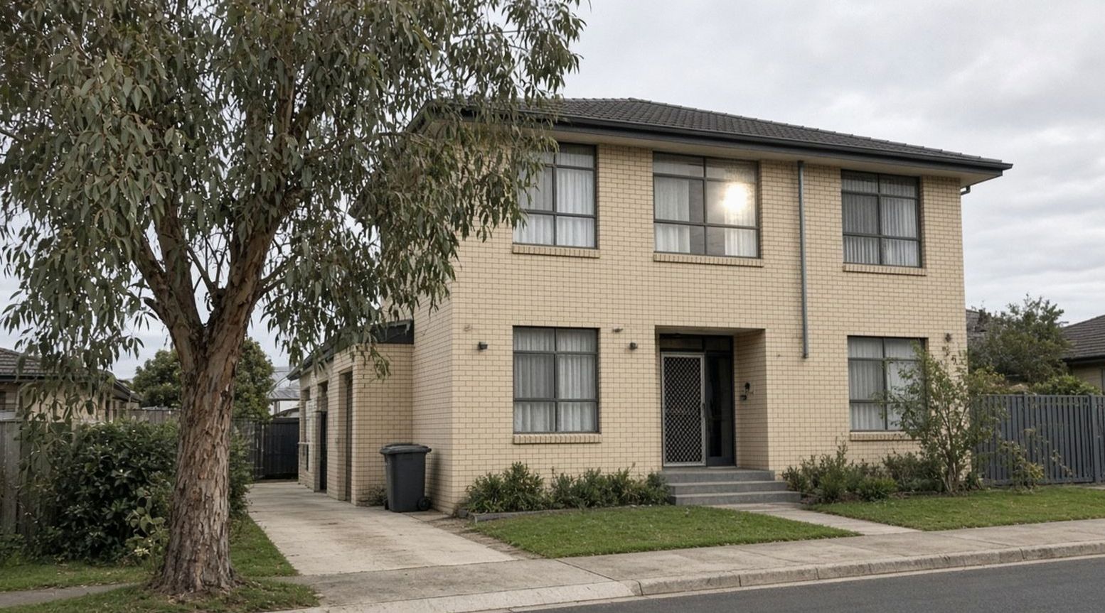 Cream-brick two-storey hotel on Morison Drive, eucalypt and a wheelie bin