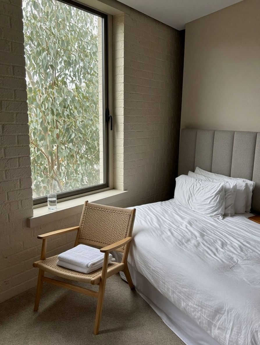 Narrower bedroom, wooden chair with towels, glass of water on the sill